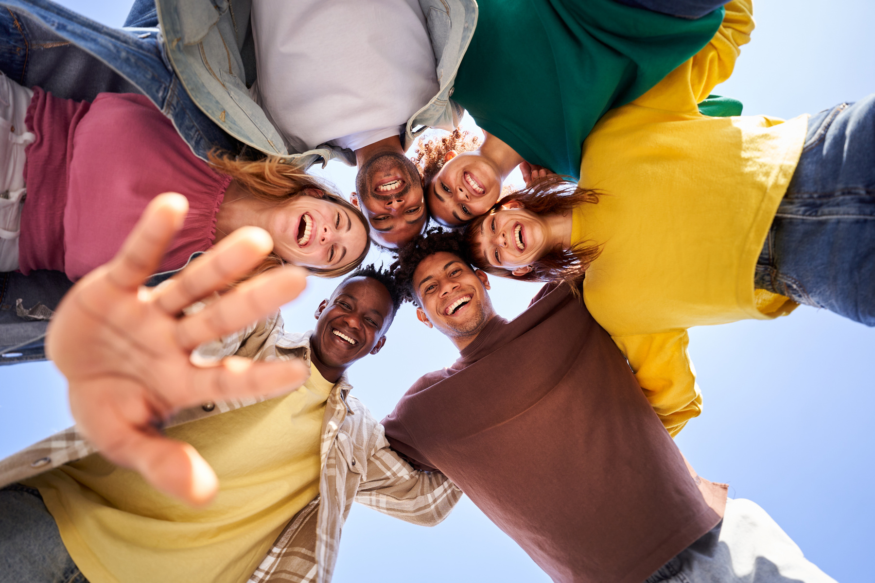 Internacional Erasmus students looking at camera cheerfully embracing each other.